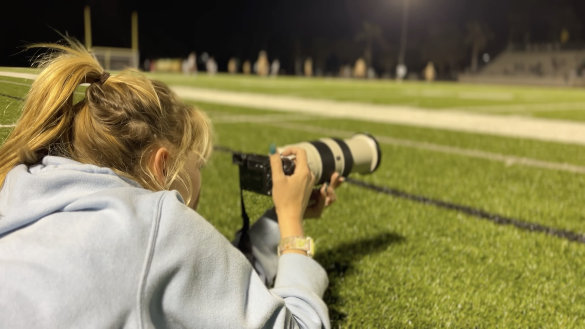 Senior Betsy Neal taking photos at a girls soccer match.